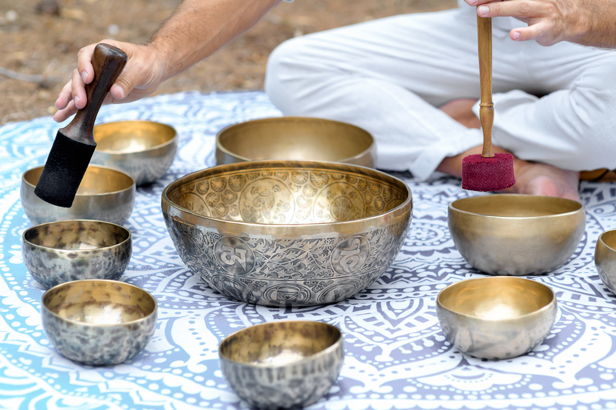 Close-up of man hands playing on a singing tibetian bowl with sticks. Sound healing music instruments for meditation